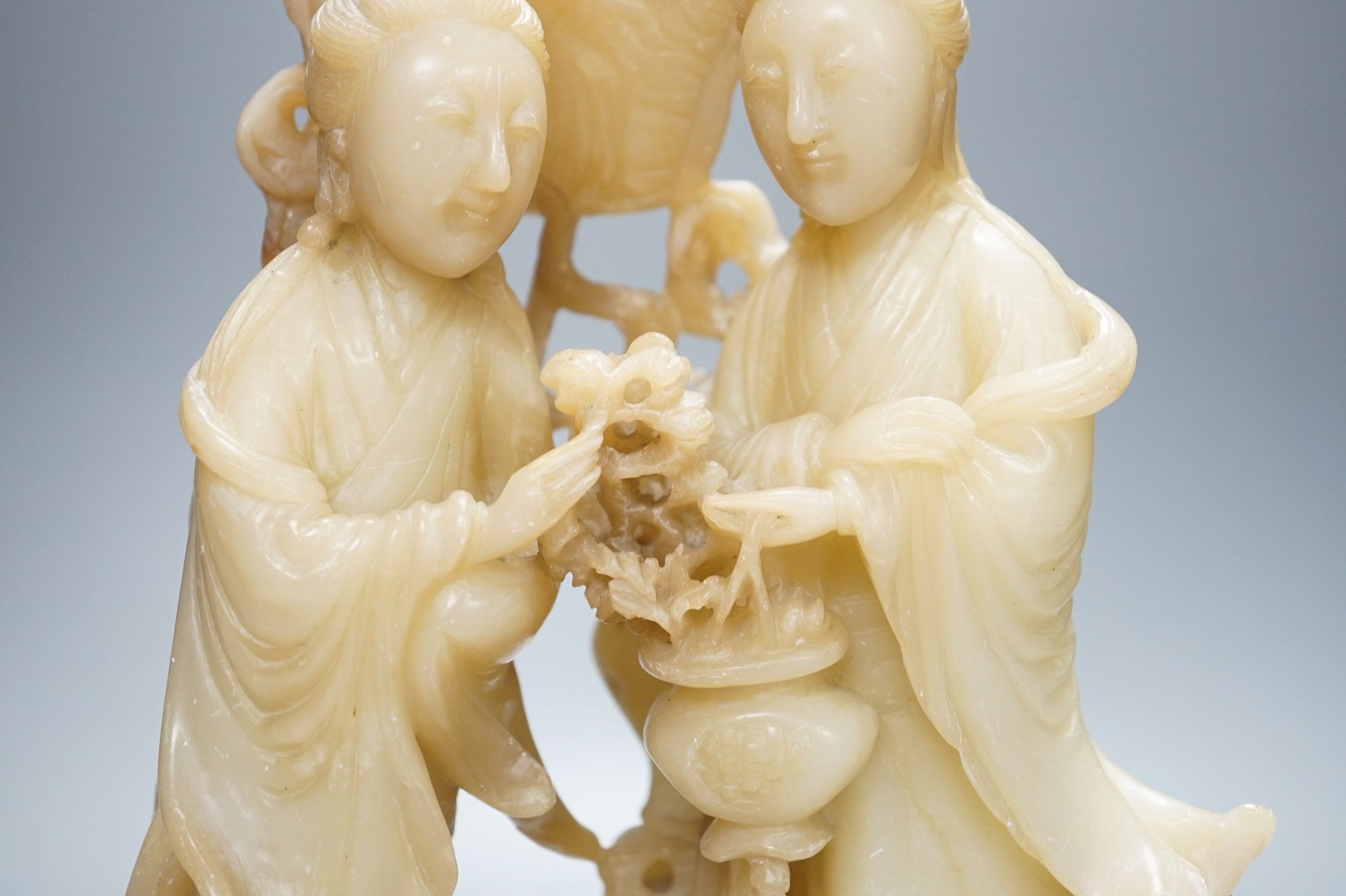 A Chinese soapstone carving of two ladies, wood stand, early 20th century, 36 cms high.